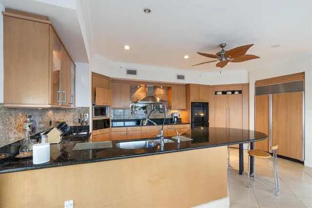 a large kitchen with stainless steel appliances a large counter top a stove a chimney a sink and a refrigerator