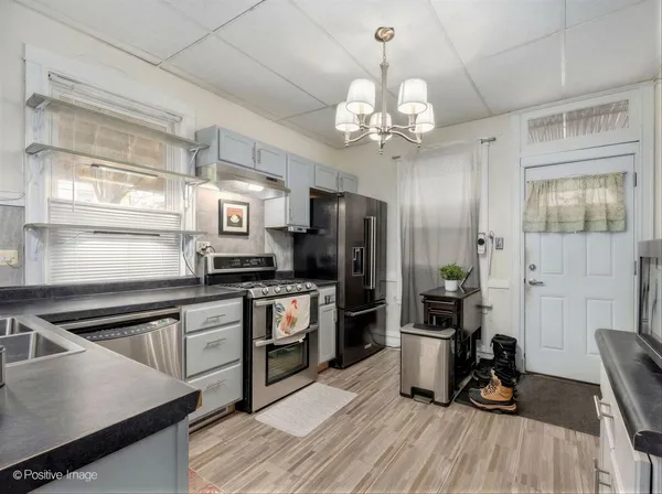 a kitchen with granite countertop stainless steel appliances cabinets a dining table and a chandelier