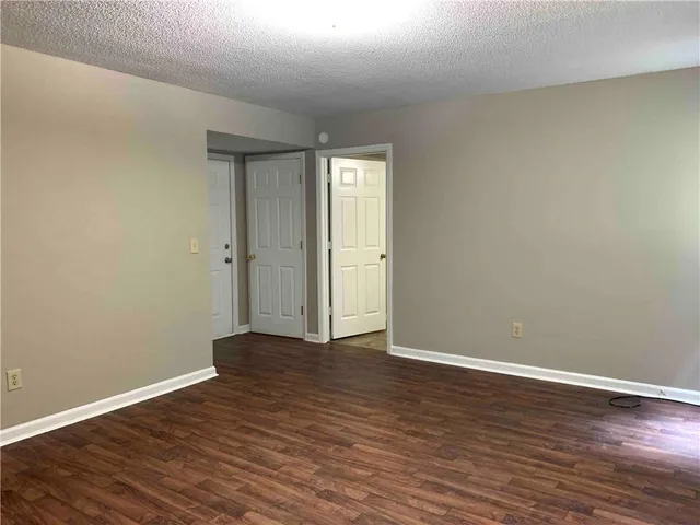 a view of an empty room with wooden floor and window