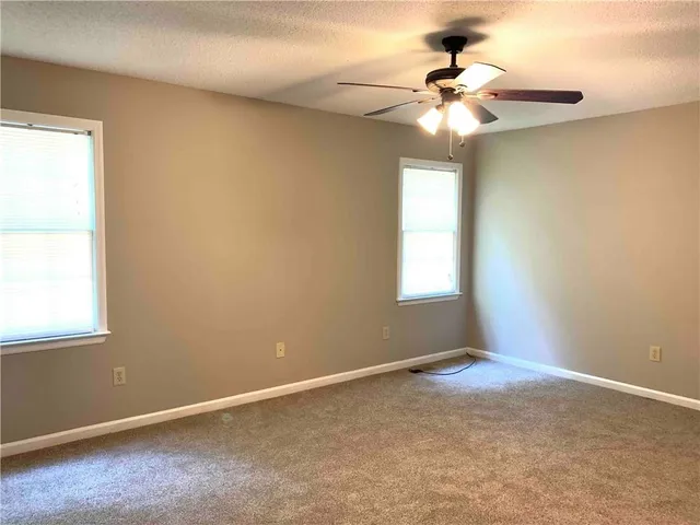 an empty room that has a window and a chandelier fan