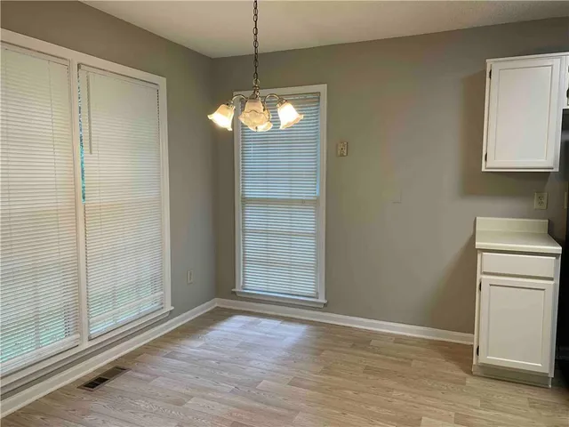 an empty room with wooden floor cabinet and windows