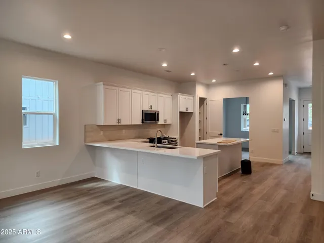 a kitchen with stainless steel appliances a sink stove and wooden floor