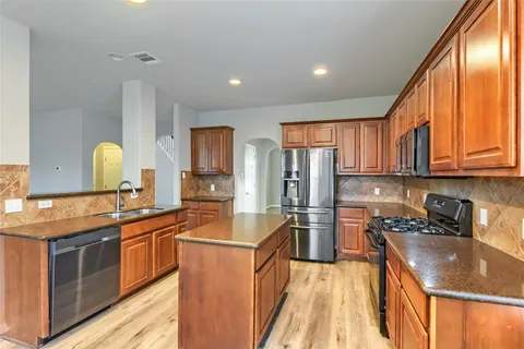 a kitchen with stainless steel appliances granite countertop sink stove refrigerator and cabinets