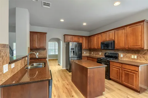 a kitchen with granite countertop wooden cabinets a stove top oven and stainless steel appliances