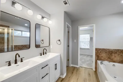 a bathroom with a double vanity sink a mirror and a bathtub