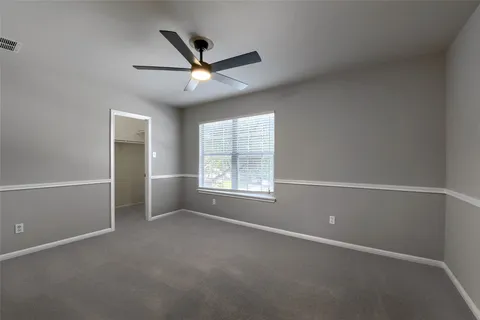 an empty room with a ceiling fan and windows