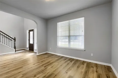 a view of an empty room with wooden floor and a window