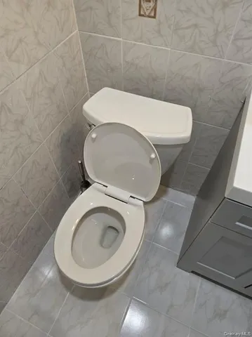 a white toilet sitting next to a white wall