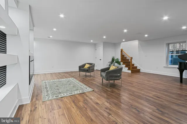a living room with furniture wooden floor and a kitchen view