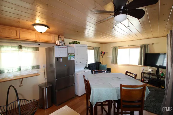 a kitchen with stainless steel appliances granite countertop a dining table chairs refrigerator and sink