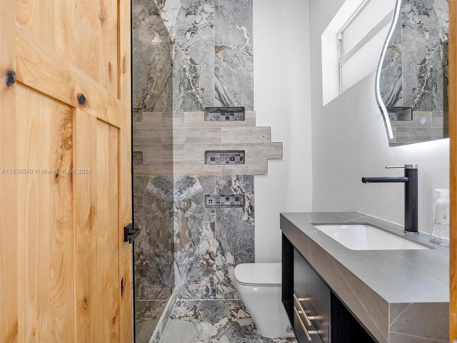 4431 Alton Road, Unit 1 Miami Beach, FL 33140 - Photo 15 of 60 a bathroom with a sink and mirror with toilet