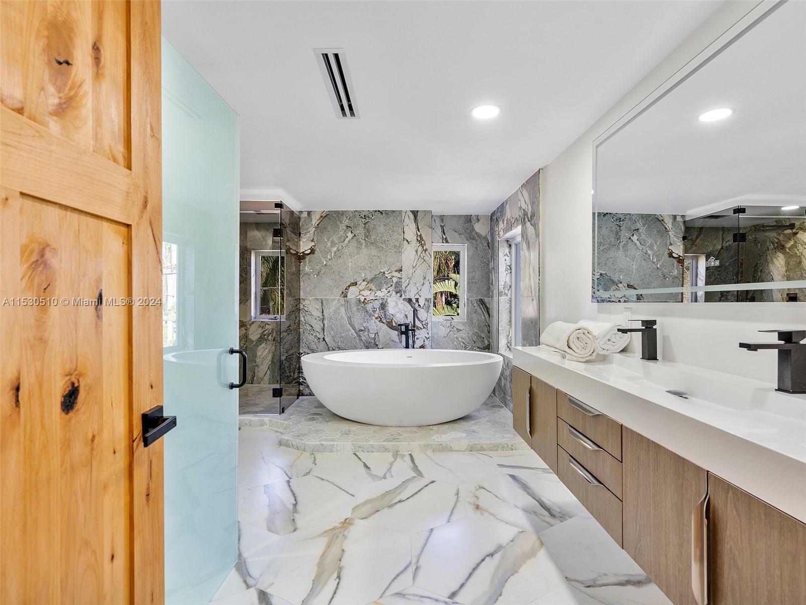 4431 Alton Road, Unit 1 Miami Beach, FL 33140 - Photo 33 of 60 a spacious bathroom with a double vanity sink a mirror and a bathtub