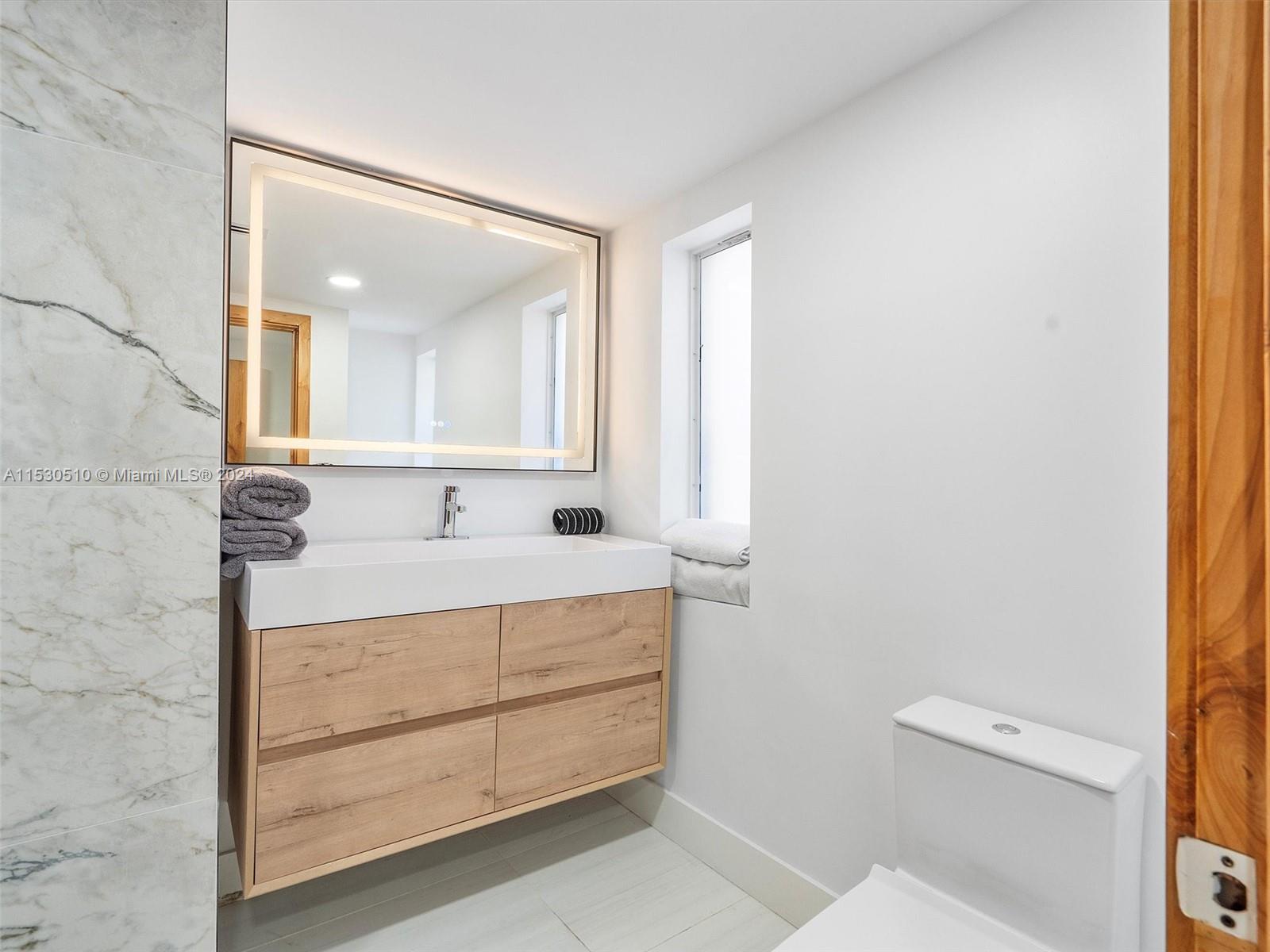 4431 Alton Road, Unit 1 Miami Beach, FL 33140 - Photo 46 of 60 a bathroom with a sink a toilet and mirror