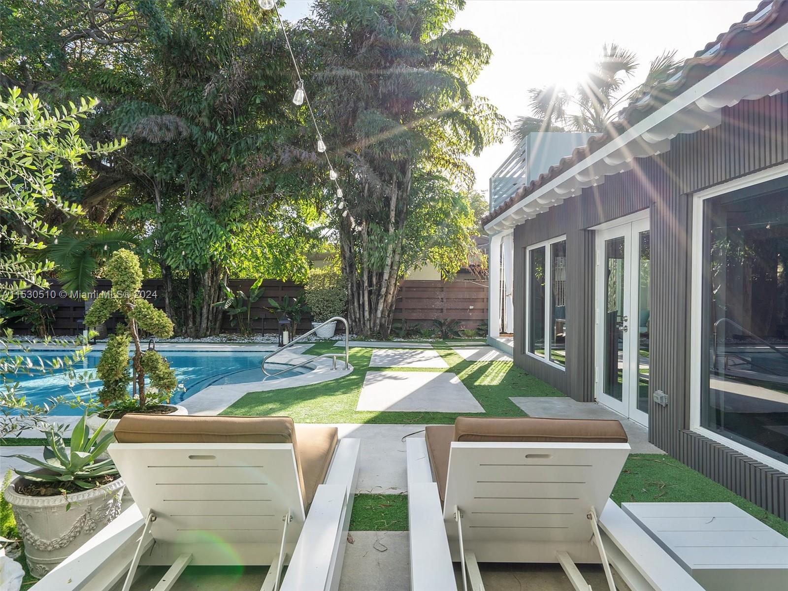 4431 Alton Road, Unit 1 Miami Beach, FL 33140 - Photo 56 of 60 a view of a patio with couches table and chairs and potted plants and large trees