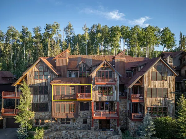 a view of a big house with large trees and lawn chairs