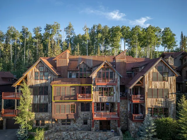 a view of a big house with large trees and lawn chairs