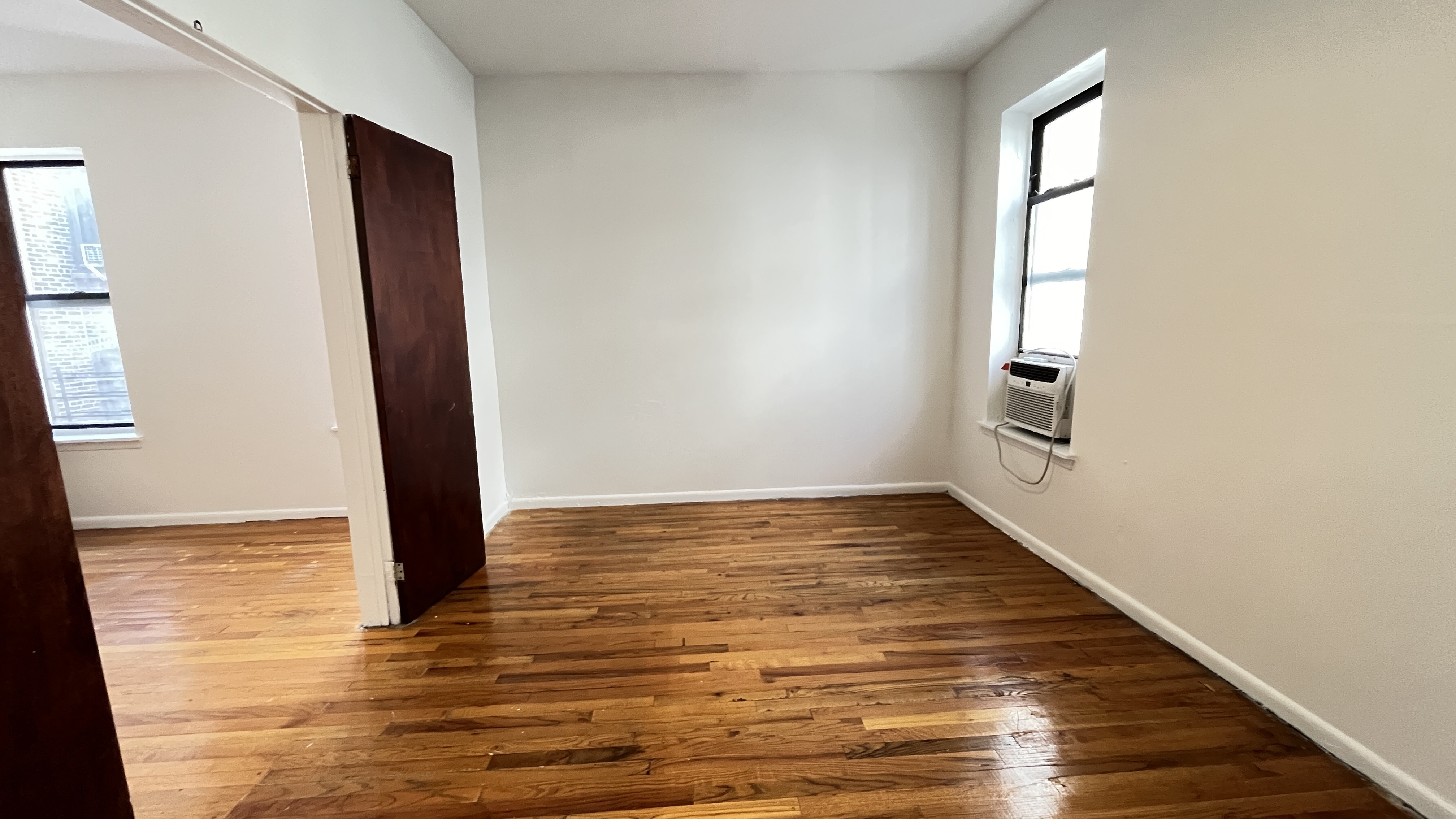 Undisclosed Address Manhattan, NY 10032 - Photo 7 of 9 a view of an empty room with wooden floor and a window