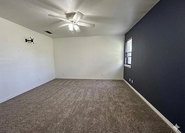 an empty room with windows and chandelier fan