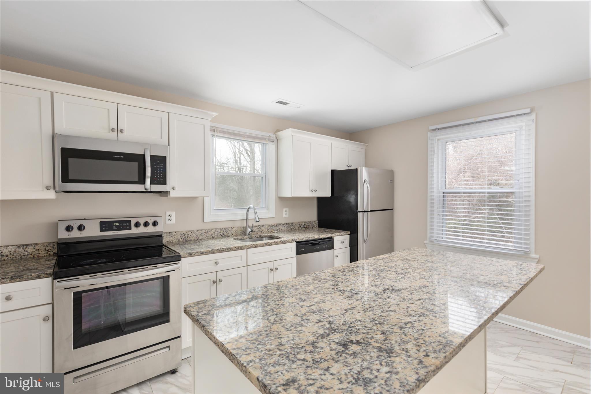 6533 Caledon Road King George, VA 22485 - Photo 10 of 32 a kitchen with stainless steel appliances kitchen island granite countertop a stove sink and microwave