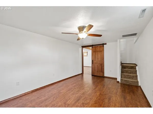 a view of an empty room with a window and wooden floor
