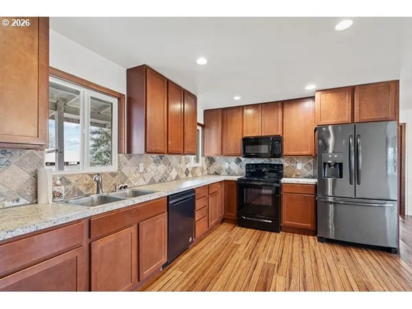a kitchen with granite countertop wooden floors stainless steel appliances a sink