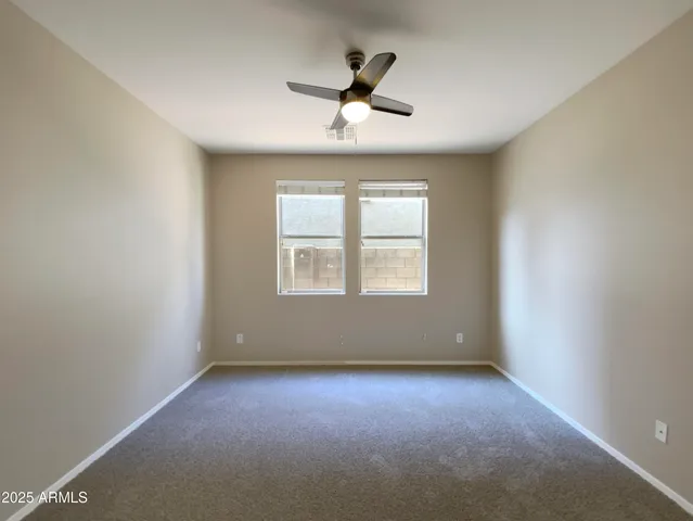an empty room with a ceiling fan and windows