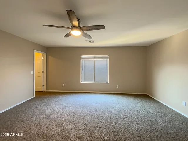 an empty room with a window and a ceiling fan