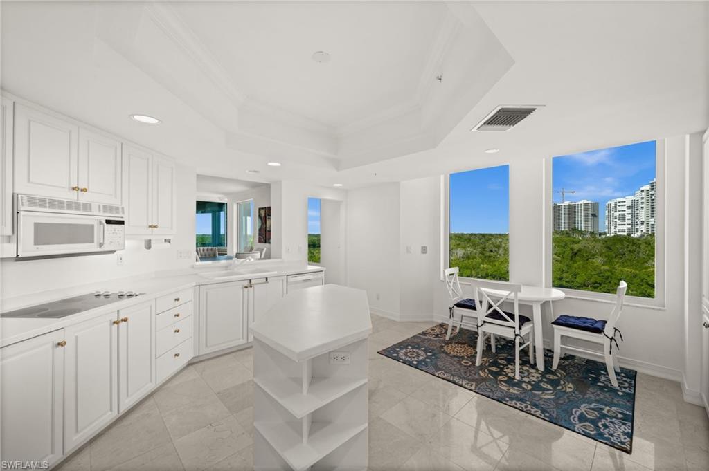 445 Dockside Drive, Unit A504 Naples, FL 34110 - Photo 14 of 50 a kitchen with stainless steel appliances kitchen island granite countertop a stove a sink a dining table and chairs