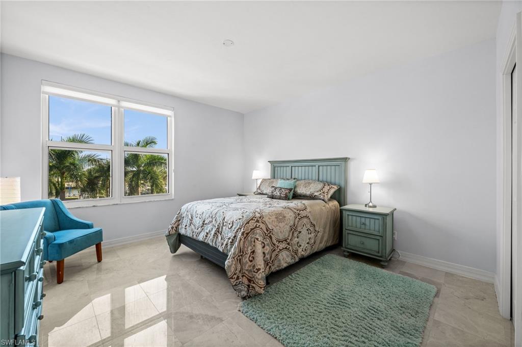 445 Dockside Drive, Unit A504 Naples, FL 34110 - Photo 25 of 50 a bedroom with a bed and chair next to a window