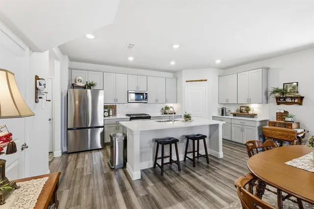 a kitchen with refrigerator a stove and wooden floor