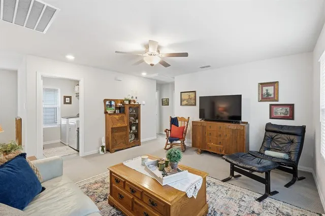 a living room with furniture a flat screen tv and kitchen view