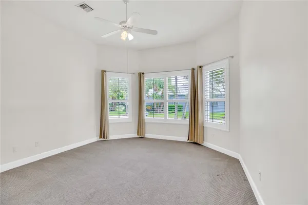an empty room with windows and chandelier fan