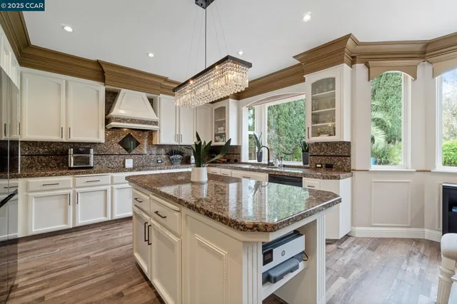 a kitchen with granite countertop a sink appliances cabinets and a counter top space