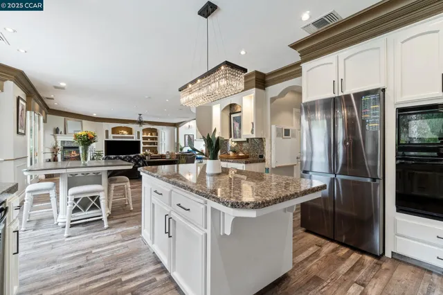 a kitchen with stainless steel appliances granite countertop a kitchen island a stove a refrigerator and a sink