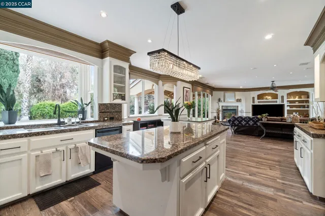 a kitchen with stainless steel appliances granite countertop a sink a stove and a wooden floors