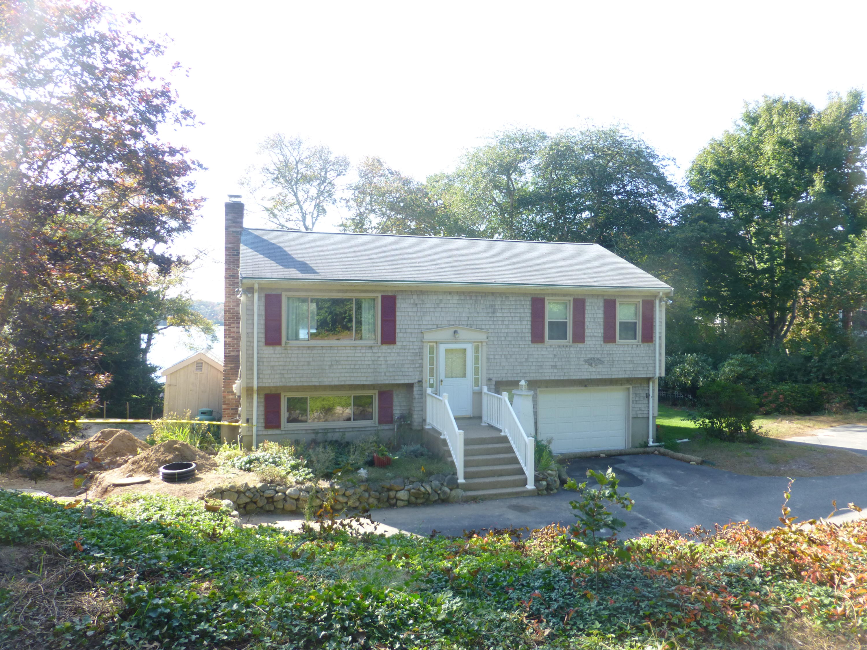 455 Huckins Neck Road Centerville, MA 02632 - Photo 4 of 32 a view of a white house next to a yard with plants and trees
