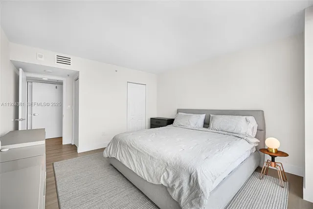a bedroom with a large bed and a flat tv screen on dresser