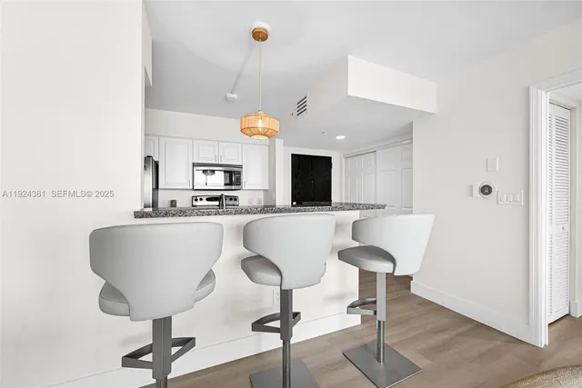 a living room with a table chairs and a kitchen view