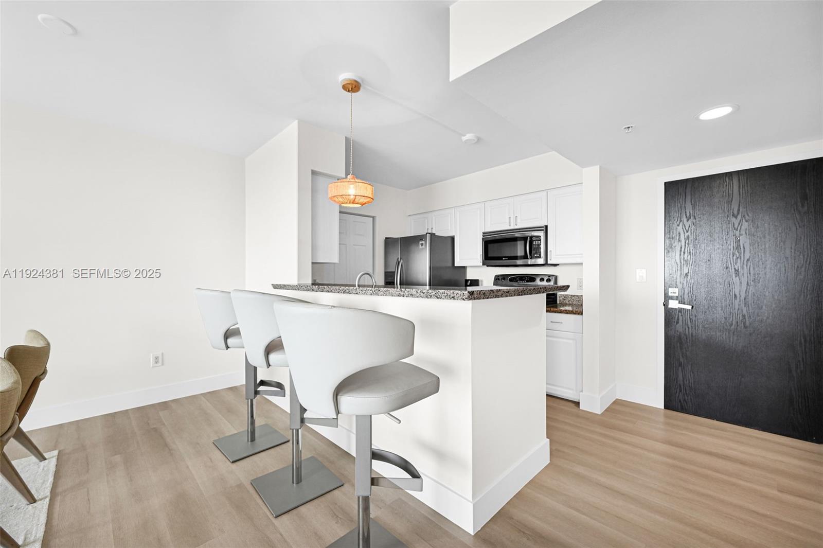 90 Alton Road, Unit 1908 Miami Beach, FL 33139 - Photo 8 of 57 a kitchen with kitchen island granite countertop a sink cabinets and wooden floor