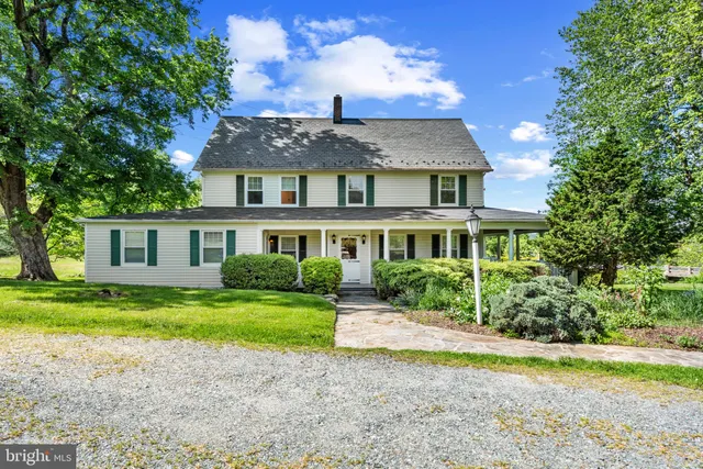 a front view of a house with a garden and trees