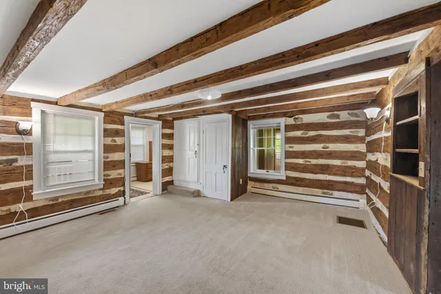 a view of an empty room with wooden walls and windows