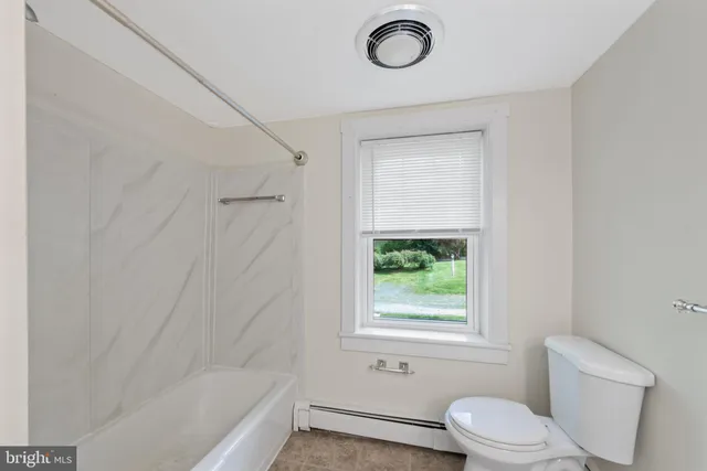 a bathroom with a toilet a window and a shower