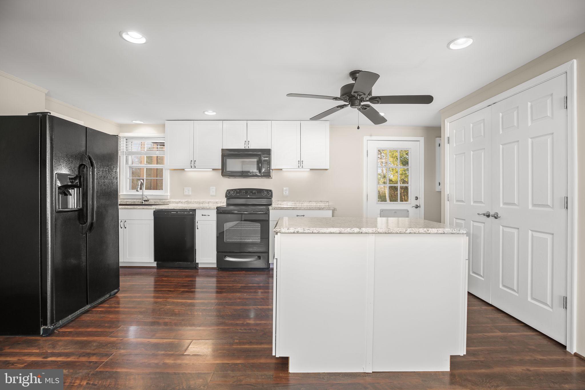 92 McCarty Road Fredericksburg, VA 22405 - Photo 7 of 39 a kitchen with kitchen island a refrigerator a stove a microwave and wooden floor