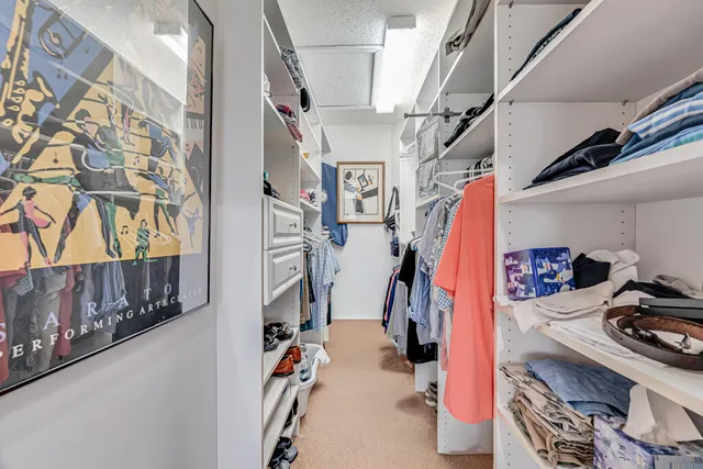 a view of walk in closet with clothes and shoes