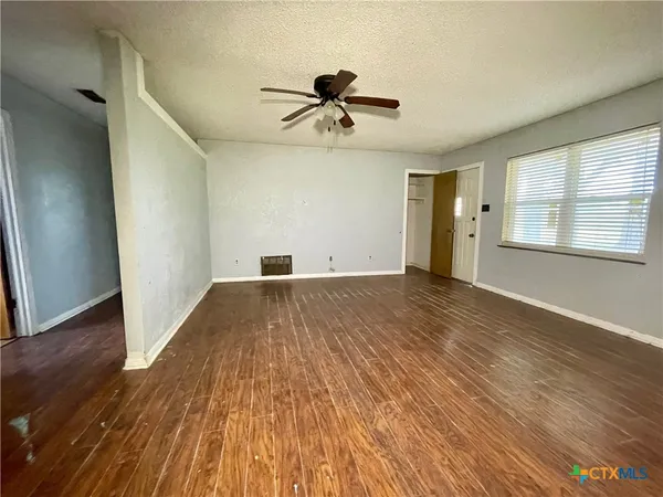 a view of empty room with wooden floor and fan
