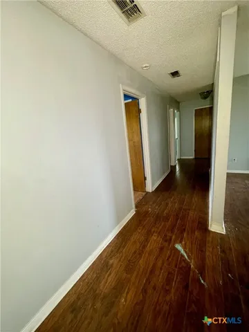 a view of an empty room with wooden floor