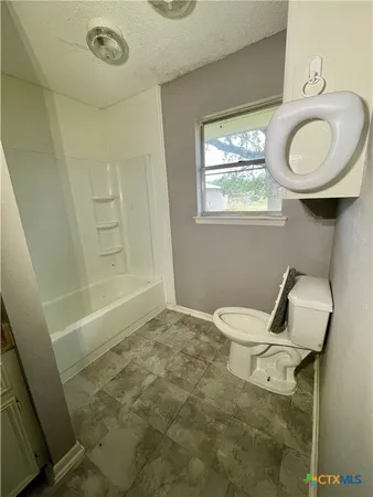 a bathroom with a toilet sink a window and mirror