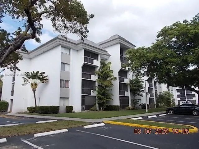 a view of a white building among the street with palm trees