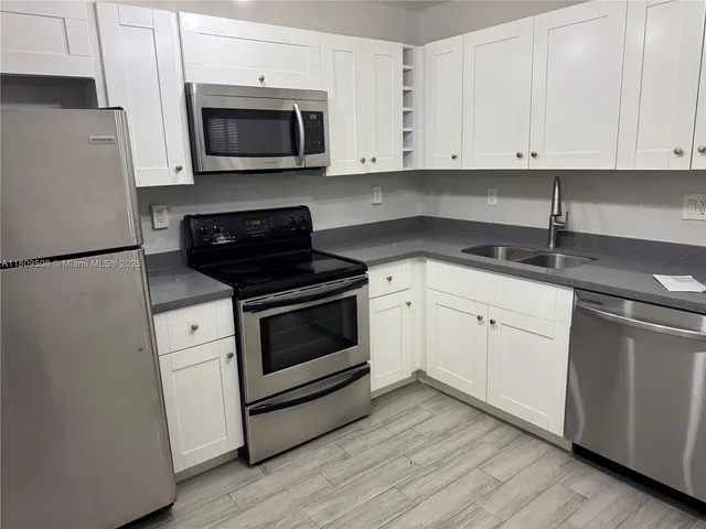 a kitchen with granite countertop white cabinets and white appliances