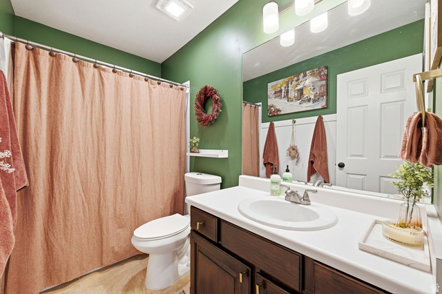 1112 Eagle Ridge Circle Sandy, UT 84094 - Photo 20 of 38 Bathroom featuring a dark wood-finish vanity with a white countertop and integrated sink, a rectangular mirror, a toilet, and a shower area